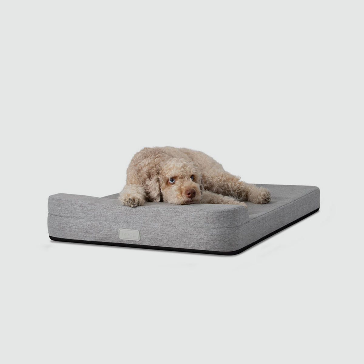 A dog laying on a Bolstr bed with its head on the bolster